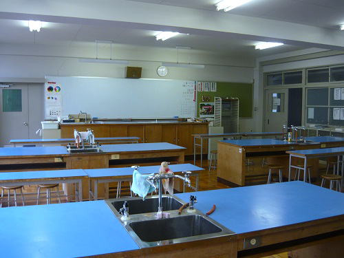 前方にホワイトボード、偶数列の机には洗面台が設備されている教室